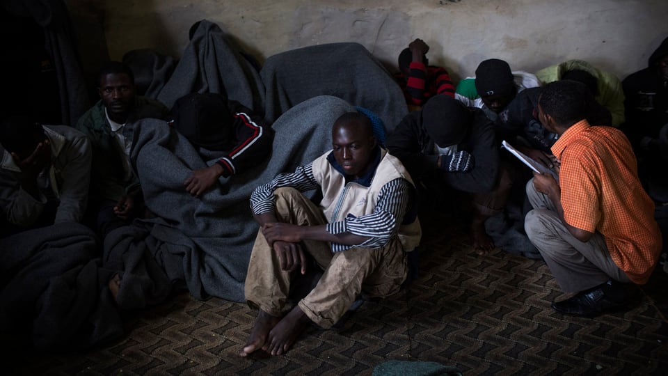 Migranten decken sich mit Decken zu, nachdem sie bei der Flucht übers Mittelmeer aufgefangen wurden.