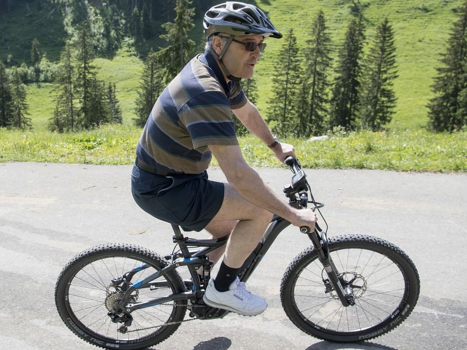 Guy Parmelin in kurzer Hose auf einem E-Bike.