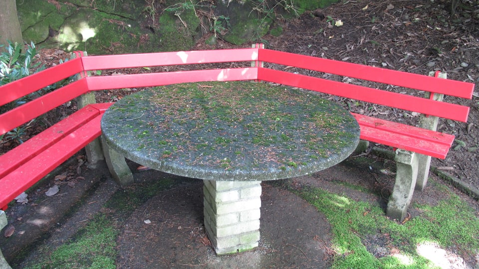Ein runder Tisch mit roten Bänken: Kleine Ruheecke im Garten der Rachmaninoff-Villa.