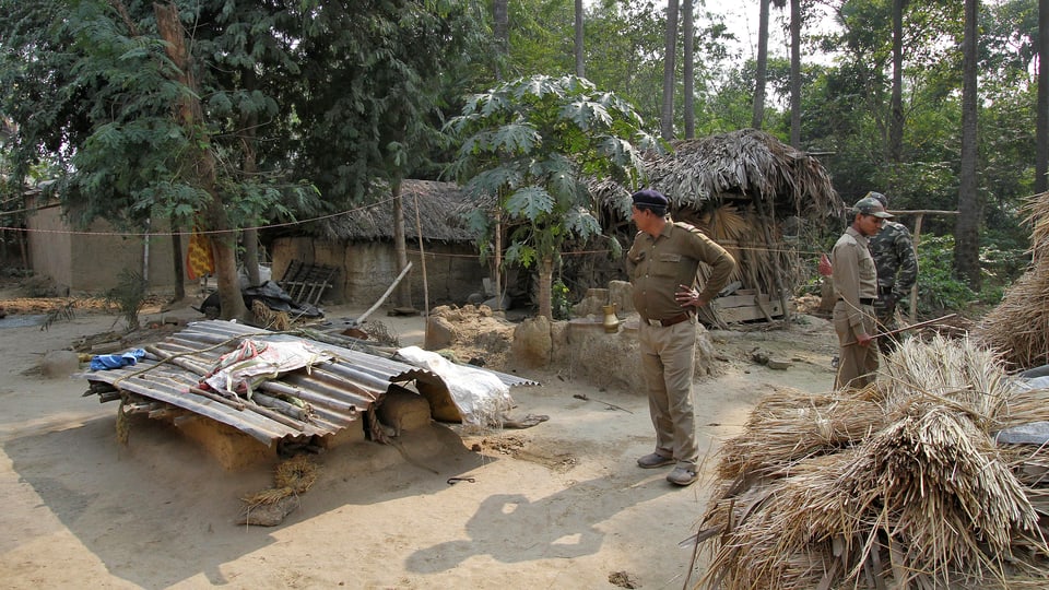 Polizisten stehen auf einem Dorfplatz in Indien.