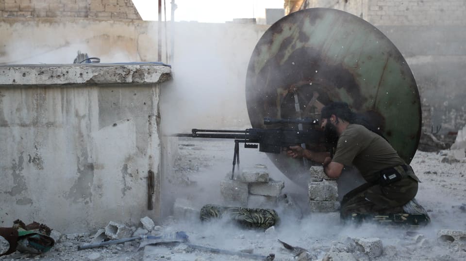 Rebelle in Aleppo kniet vor einem Maschienengewehr.