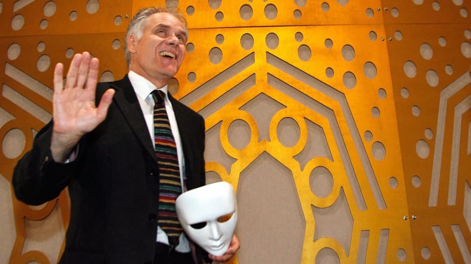 Moritz Leuenberger an der Einweihung des romanisches Theaters im Jahr 2006. Er hält eine Maske in der Hand.