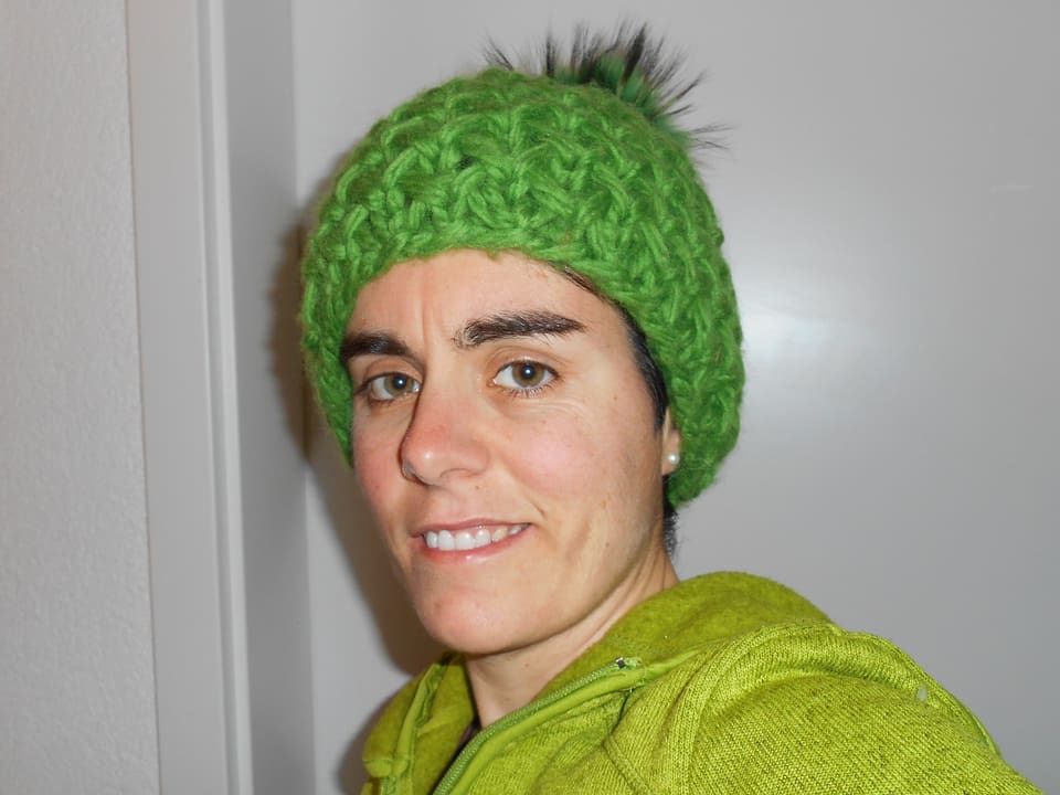 Frau mit grüner gehäkelter Kappe.