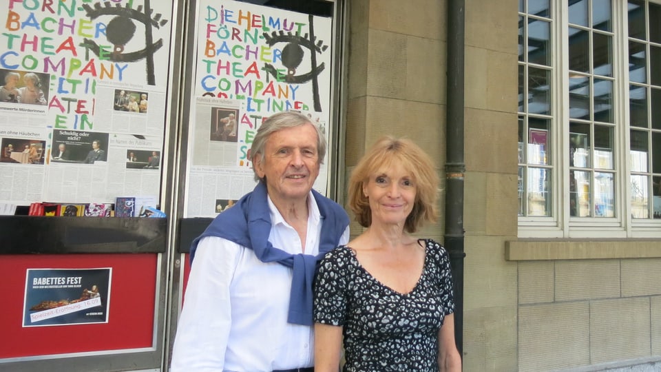 Ein Mann und eine Frau stehen vor Theaterplakaten
