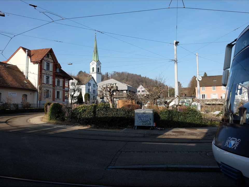 Im Vordergrund rechts ist ein Tram, im Hintergrund sind Kirche und alte Häuser zu sehen.