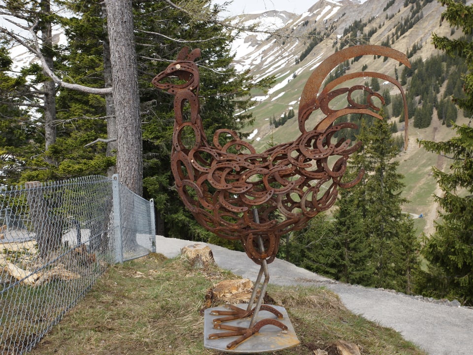 Ein grosses Kunstwerk aus rostigem Metall, das einen Hahn darstellt.