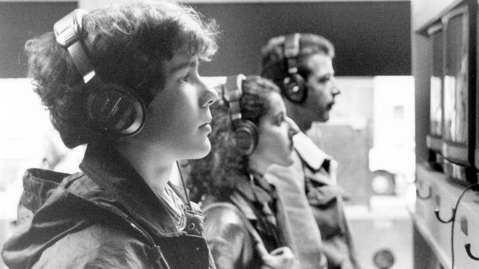 schwarzweiss Foto eines jungen Teenagers, seitlich im Profil, mit Kopfhörern, schaut auf einen Bildschirm