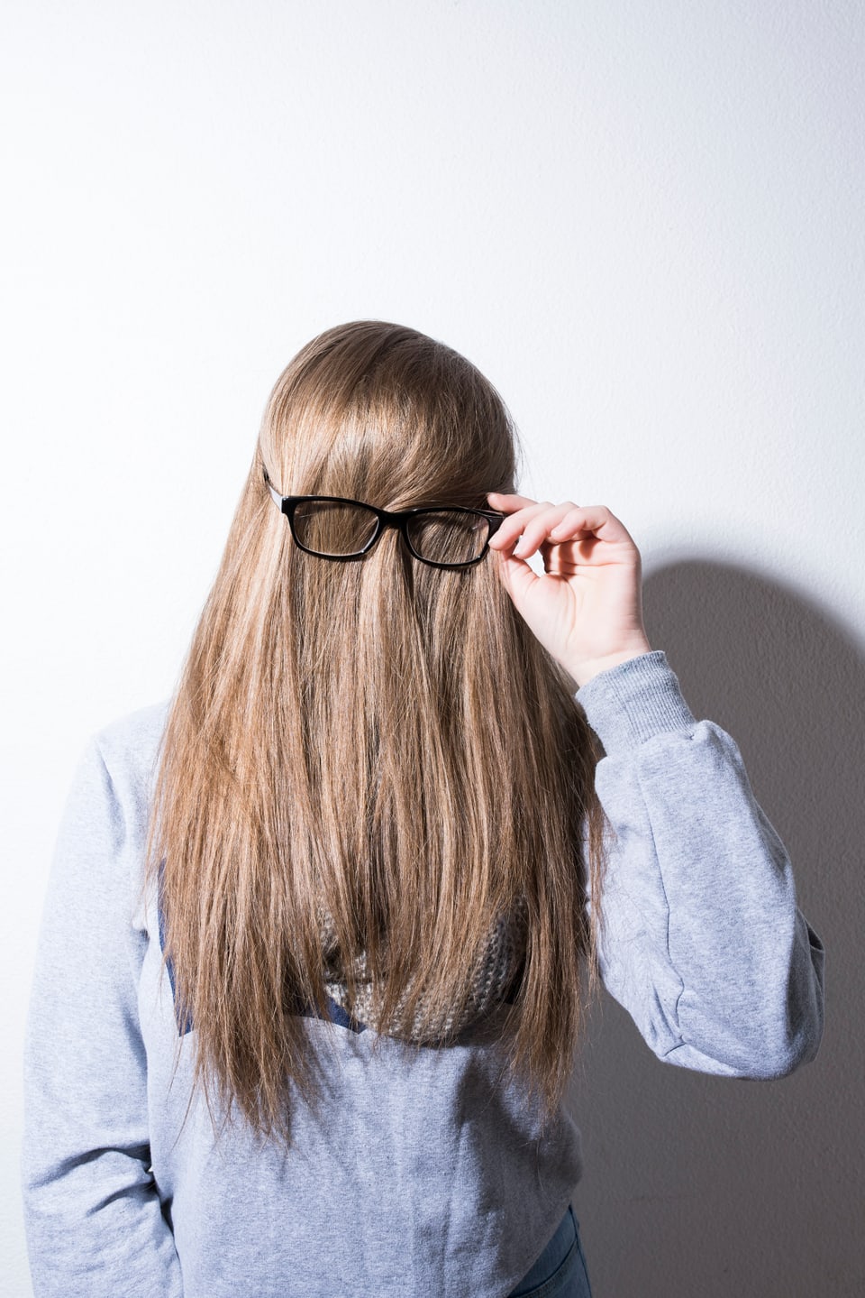Eine Frau hat die Haare nach vorne gekämmt, so dass man sie nicht kennt. Und eine Brille aufgesetzt.