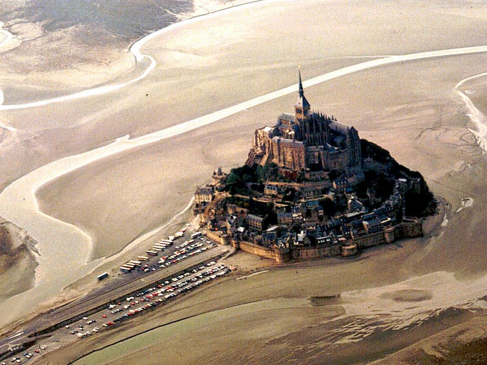 Luftaufnahme des Mont Saint Michel mit der Zufahrtstrasse.