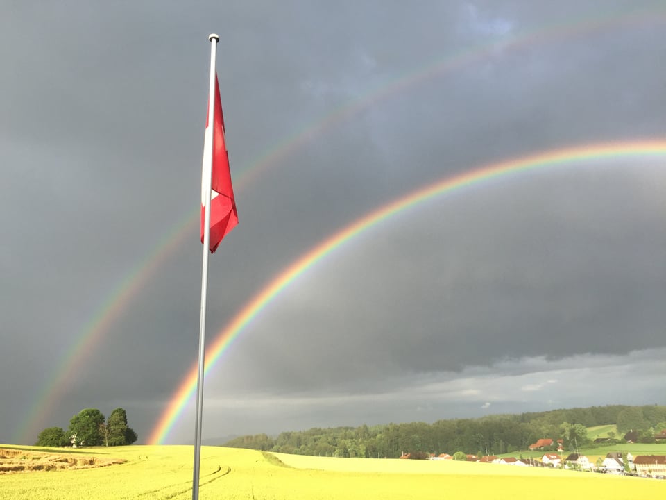 Zwei Regenbogen und eine Schweizer Fahne.