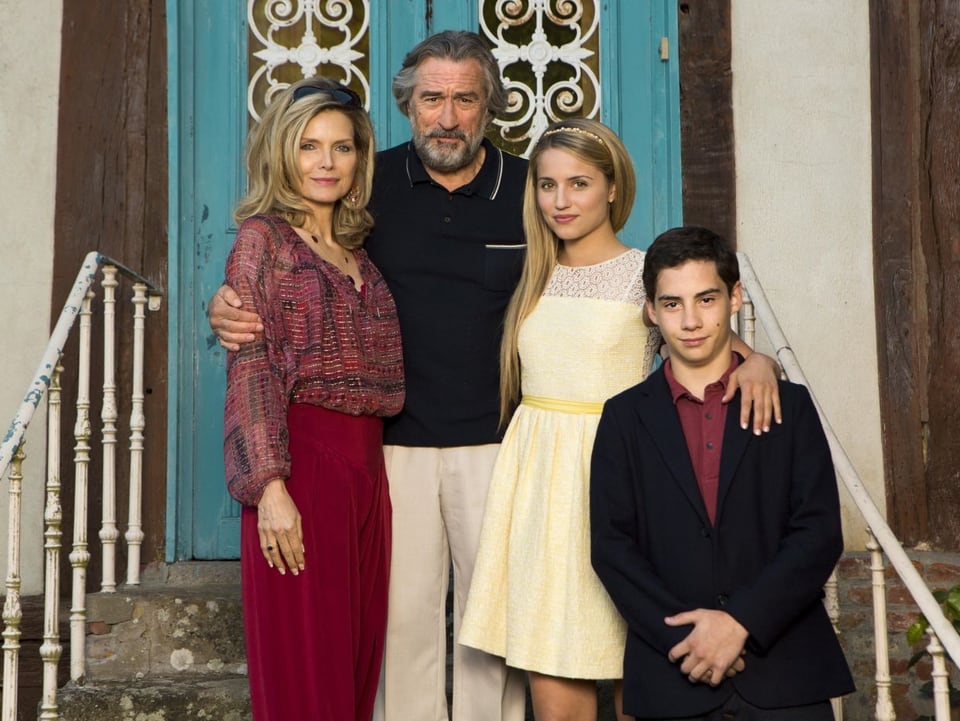 Eine Familie (unter anderem Michelle Pfeiffer und Robert de Niro) steht auf der Treppe vor einer Haustür.