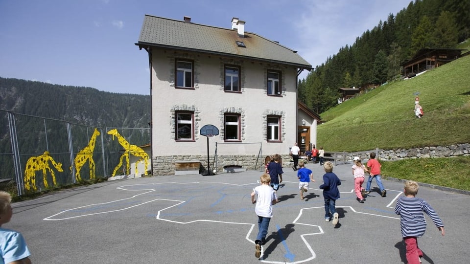 Kinder beim Kicken auf dem kleinen Pausenplatz eines Bergdorfs.
