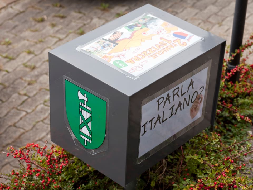 Briefkasten von Teubers beklebt mit «2 Familien 1 Schweiz» Logo, dem Kantonswappen von St. Gallen und einem Anschlag mit der Frage «Parla Italiano?»