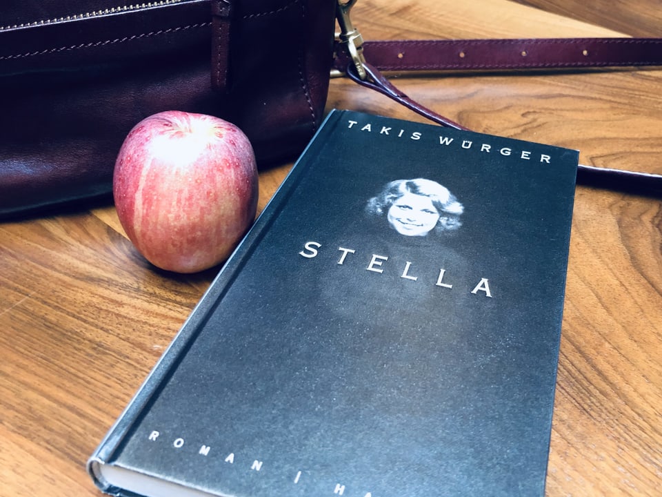 Der Roman «Stella» von Takis Würger liegt auf einem Tisch. Daneben Handtasche und Apfel