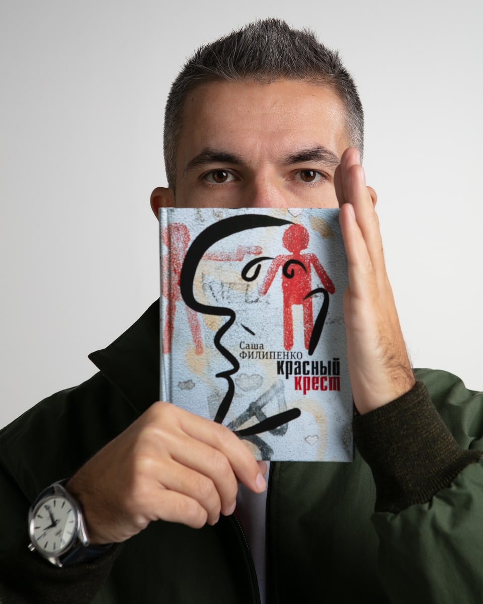 Ein Mann versteckt seinen Mund und seine Nase hinter einem Buch.