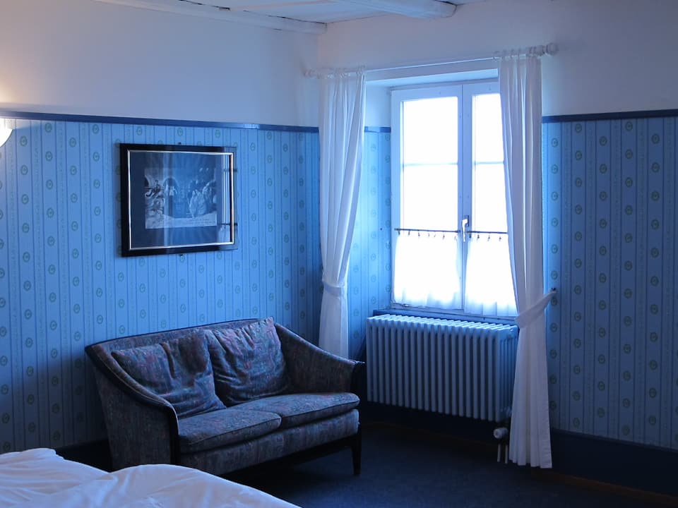 Blick in ein Zimmer mit blauer Tapete.