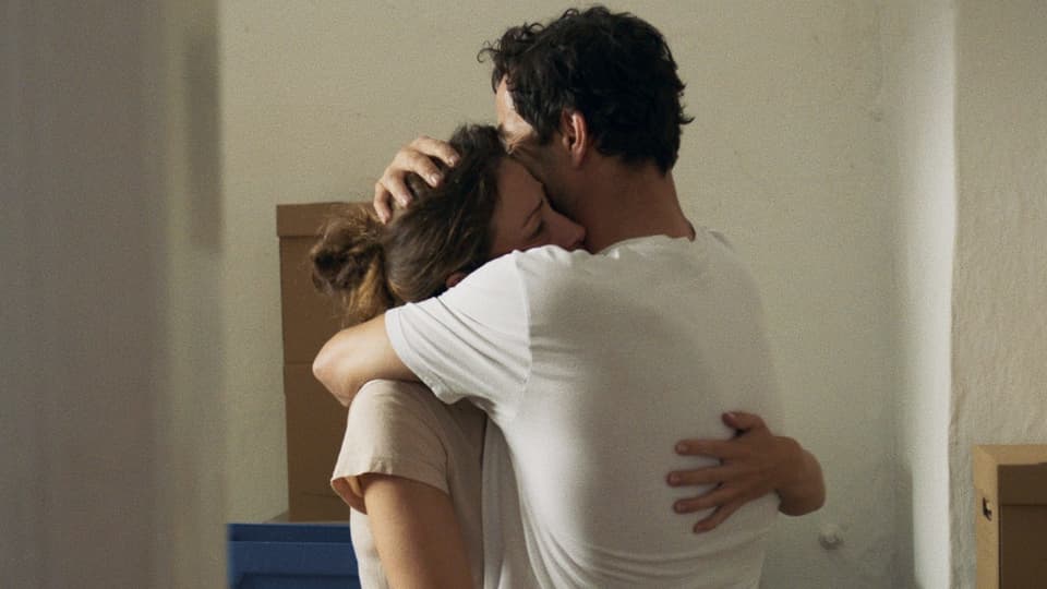 Eine Frau und ein Mann umarmen sich in einer leeren Wohnung. 