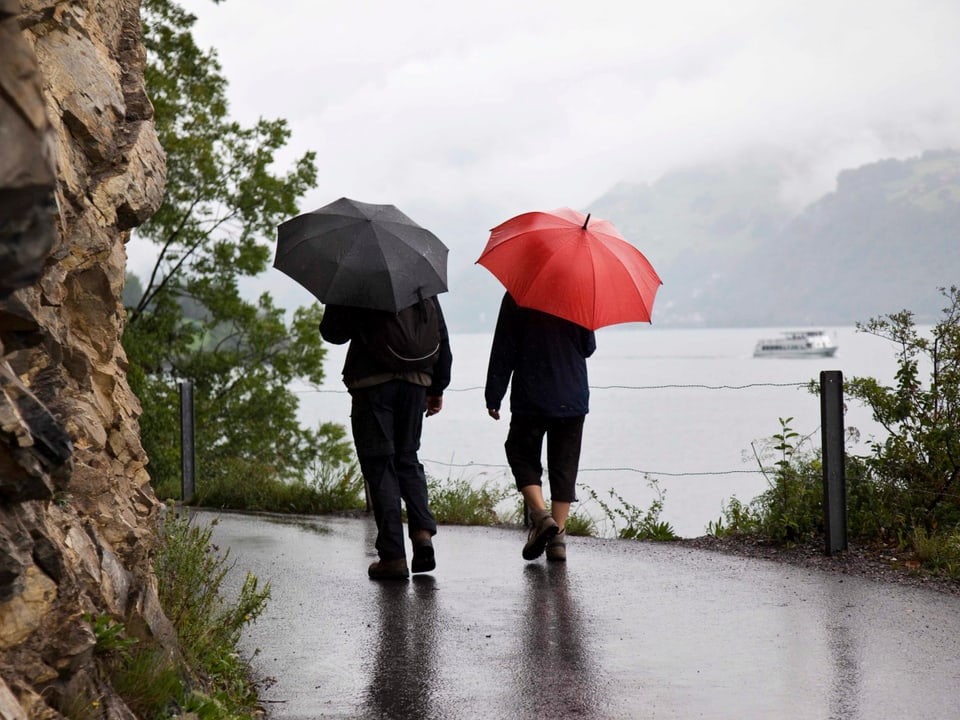 Zwei Wanderer mit Regenschirm am Ufer des Walensees