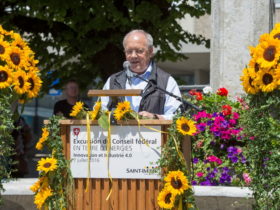Johann Schneider-Ammann umringt von Sonnenblumen während einer Ansprache.
