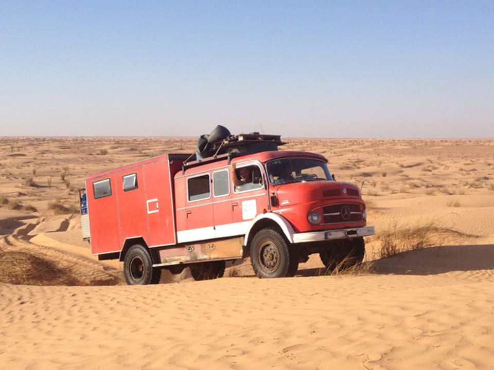 Ein roter, umgebauter Truck in der Wüste von Tunesien