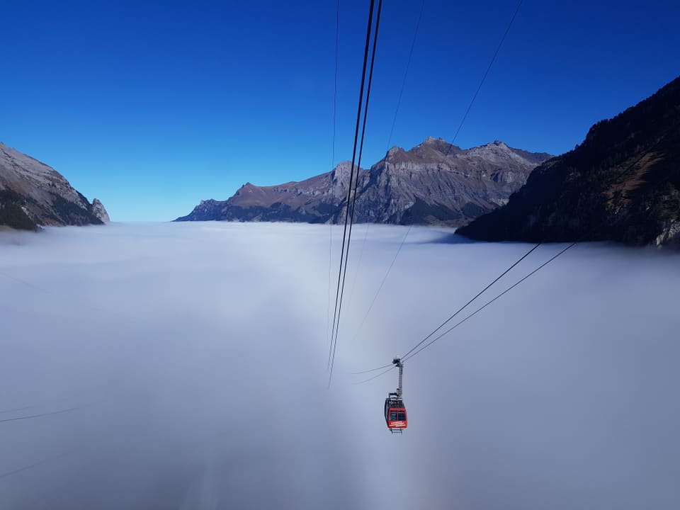 Nebelmeer mit Seilbahn aus dem Nebel an die Sonne. 