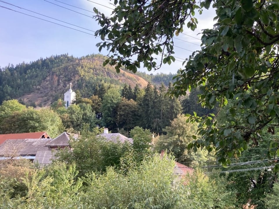 Eine Kirche und Häuser inmitten einer hügeligen Landschaft.