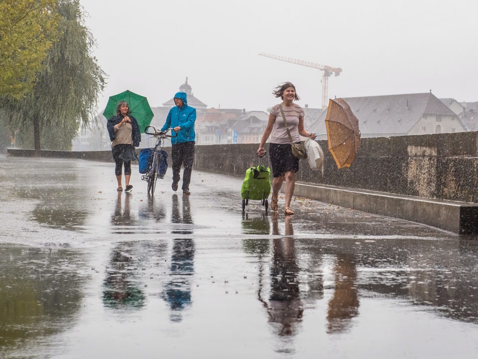 Drei Personen spazieren in starkem Regen