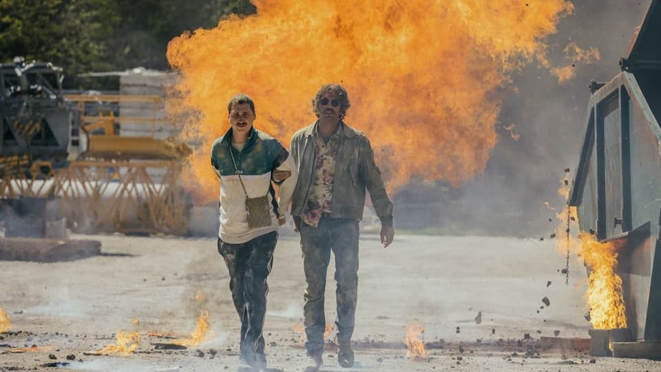 Zwei Männer laufen einer Explosion davon.