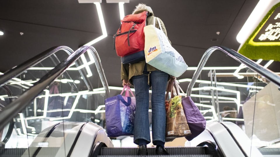 Frau auf Rolltreppe mit grossen Einkaufstaschen