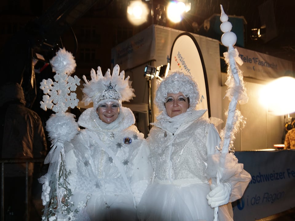 Zwei Frauen in weissen Kostümen mit grossen Schneeflocken.