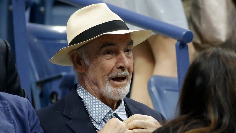 Sean Connery trägt einen Hut und ein blau-weisses Hemd und lacht.