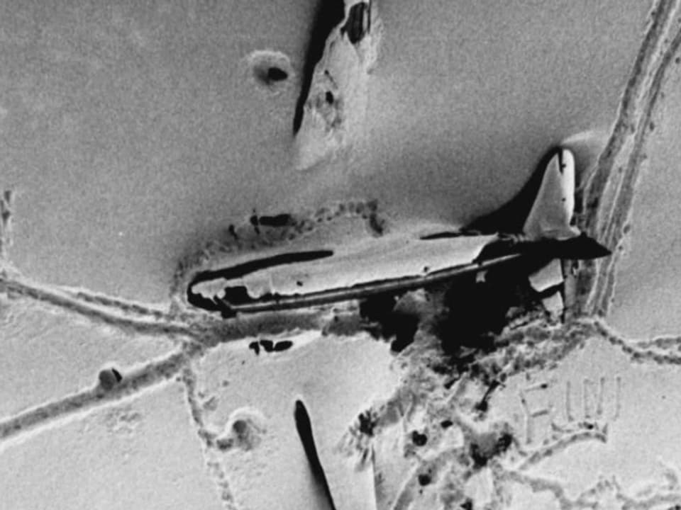 schwarzweiss: ein Flugzeug liegt mit zerbrochenem Flügel in Schnee und Eis