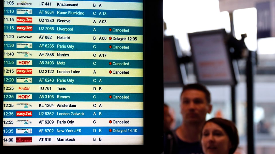 Flugpassagiere blicken auf die Anzeigetafel.
