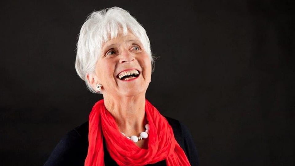 Eine lachene Frau mit kurzen, grauen Haaren.