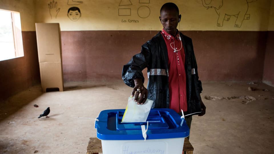 Malischer Bürger steckt einen Wahlzettel in eine Wahlurne.