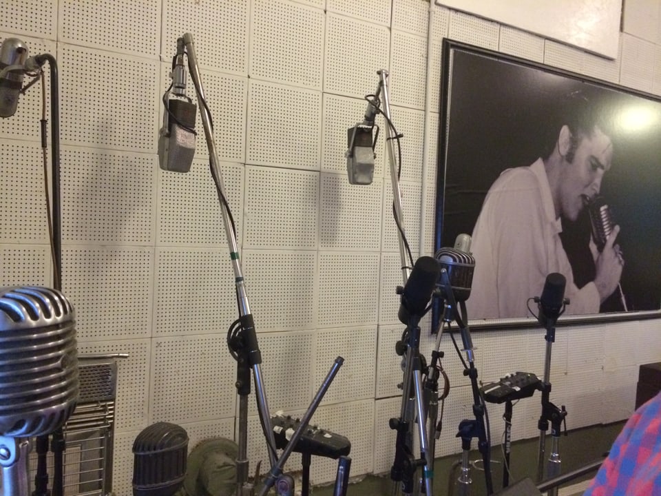 Mikrofone lehnen an einer Wand an der auch ein Bild von Elvis hängt.