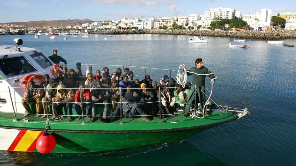 Ein Boot der spanischen Küstenwache fährt mit rund einem Dutzend Menschen an Bord im Hafen ein.