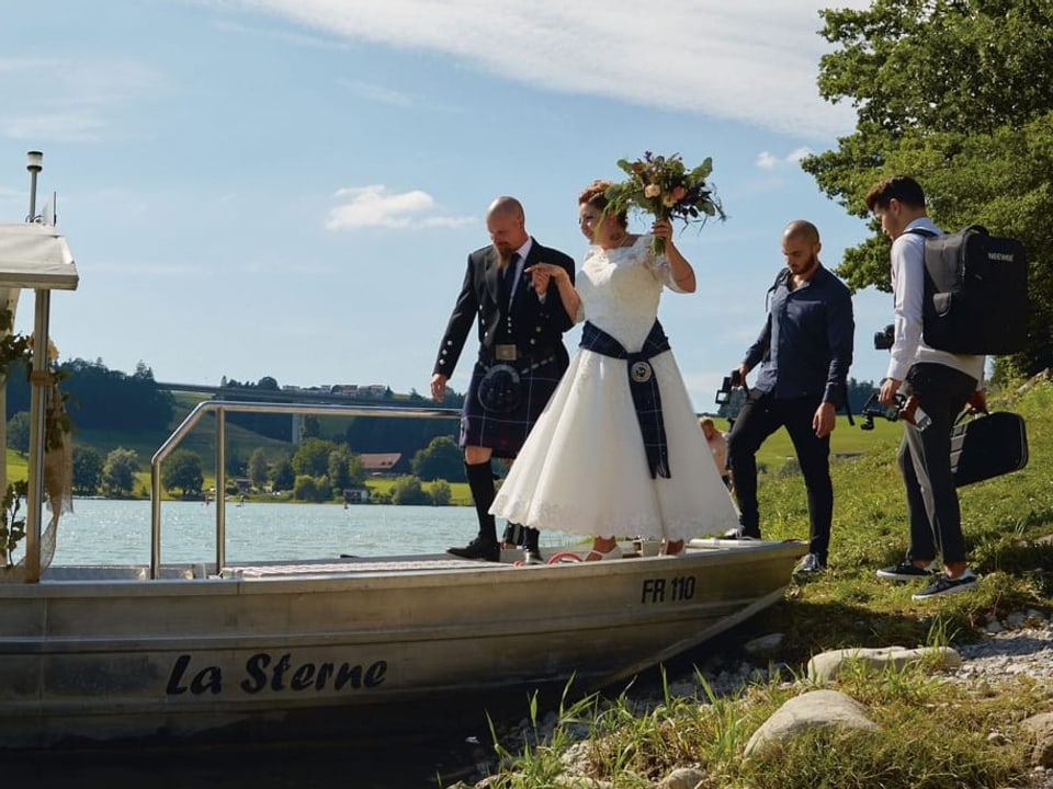Eine Hochzeitspaar steigt auf ein Boot.
