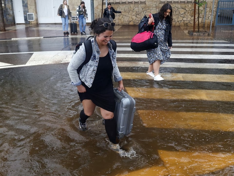 Mehrere Frauen gehen durch eine überflutete Strasse.