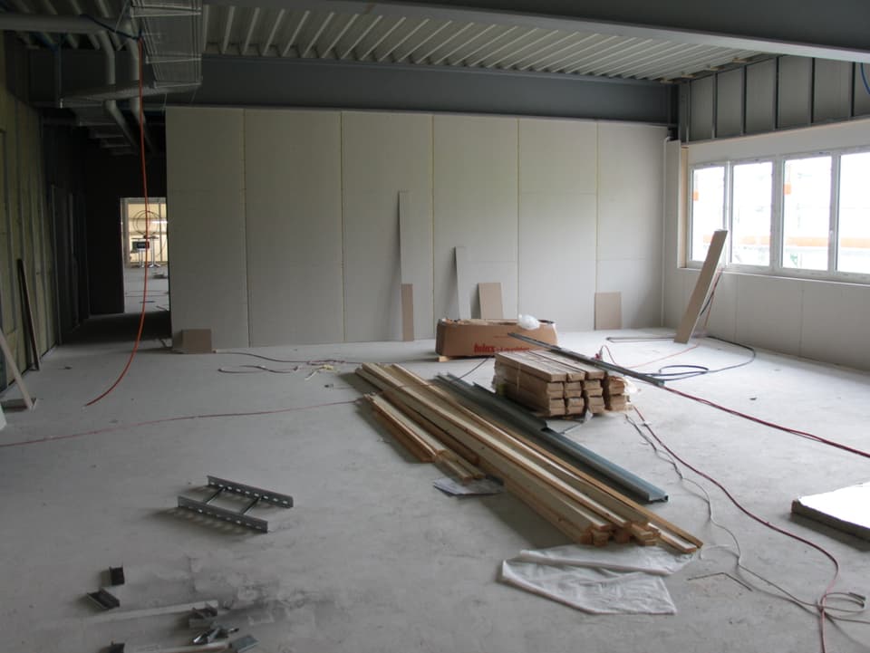 Infustriehalle im Bau mit Holzlatten am Boden.