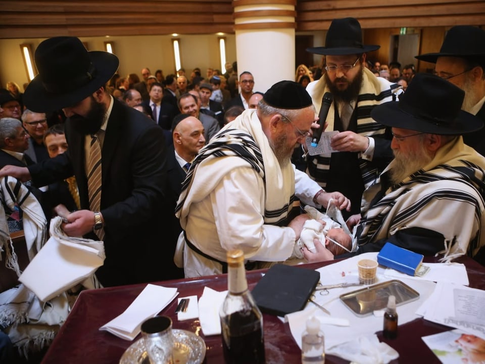 Orthodoxe Juden mit einem Rabbiner, kurz vor einer Beschneidung.