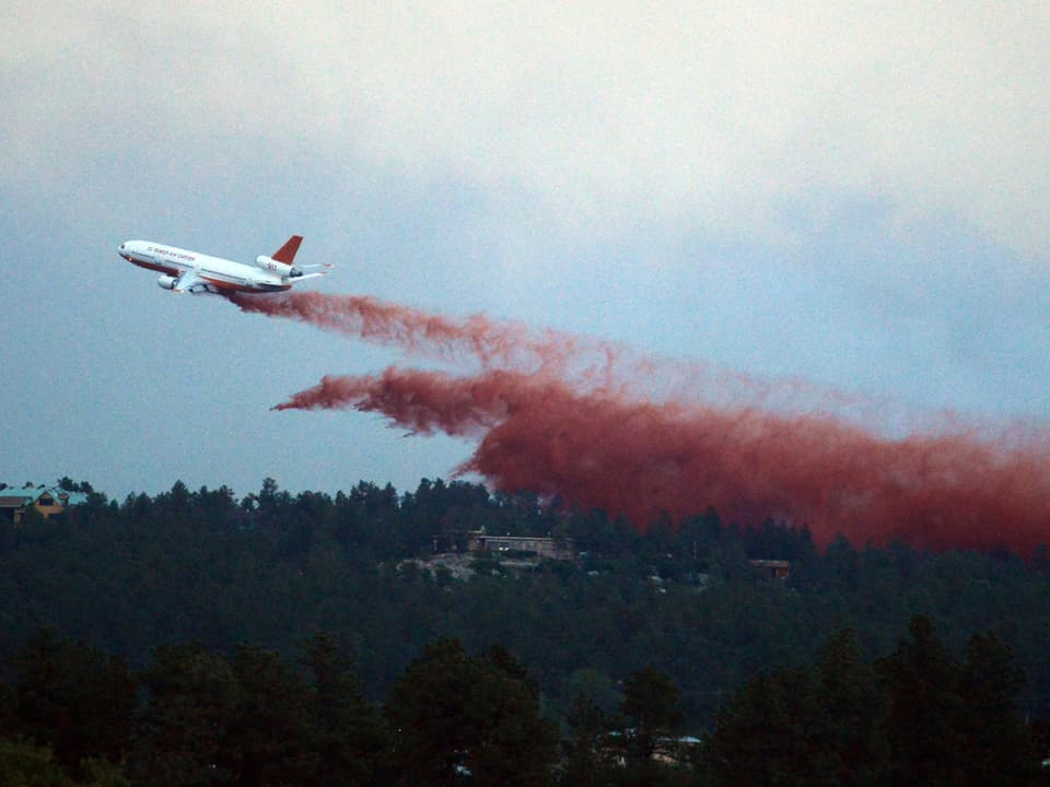 Ein Löschflugzeug (DC-10) lässt Wasser ab über dem Waldbrand.