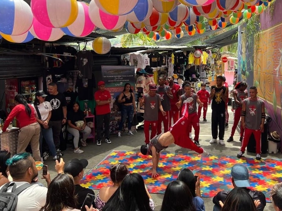 Street performers dance under colorful lights in front of an audience.