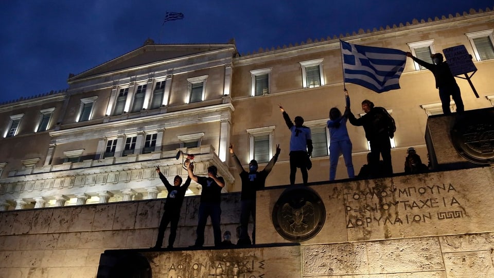 Menschen vor dem griechischen Parlament mit Griechen-Flagge.