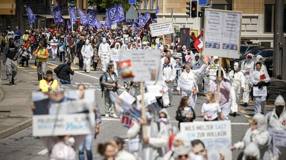 Weiss gekleidete Leute mit Transparenten und Bannern demonstrieren in Neuenburg. 