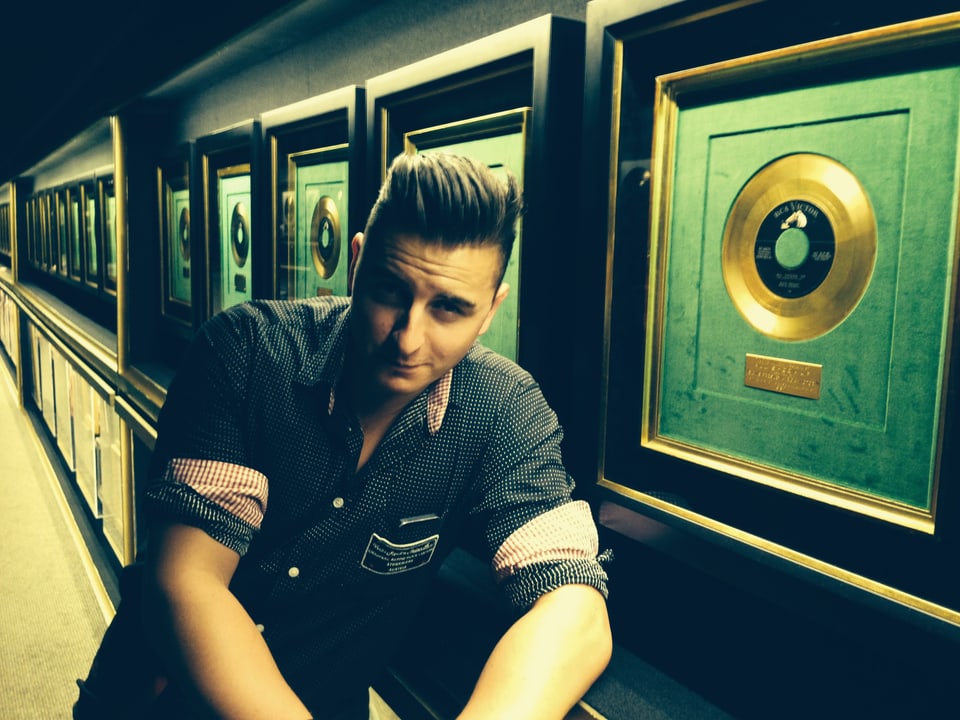 Andreas Gabalier vor einer Wand mit goldenen Schallplatten.