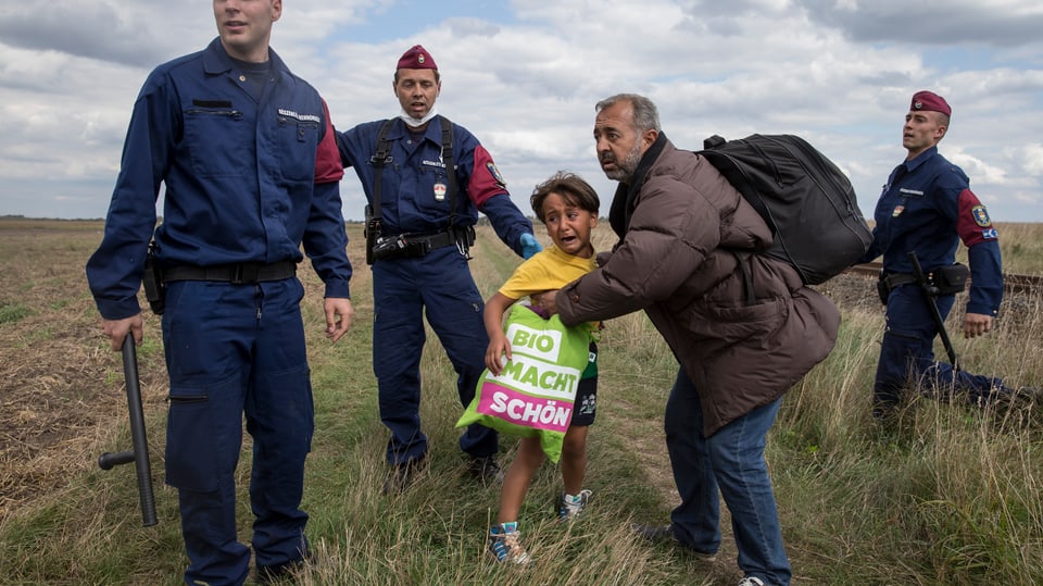 Ein Flüchtling mit seinem Sohn, von ungarischen Polizisten umrundet