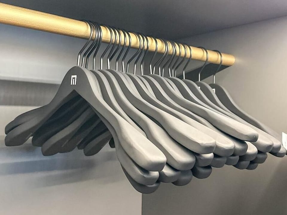 Schwarze Kleiderbügel hängen in einem Schrank