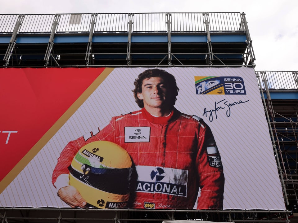 Grosses Plakat an einem Gebäude mit Bild von Ayrton Senna, berühmter Rennfahrer, mit Helm in der Hand.