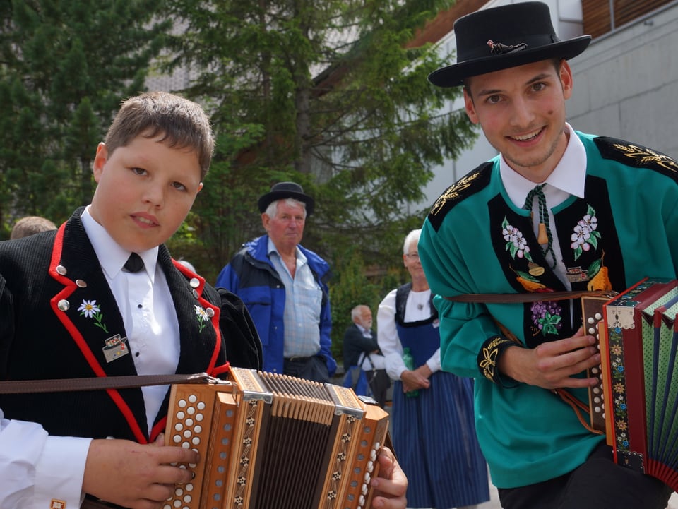 Zwei junge Musikanten in Bündner Tracht mit Schwyzerörgeli.